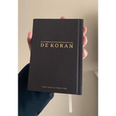 Donkere boekband met goudgeletterde titel van de Koran met Nederlandse vertaling